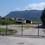 ograda klizna vrata zelena površina kuća u pozadini