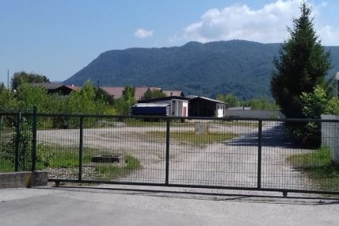 ograda klizna vrata zelena površina kuća u pozadini